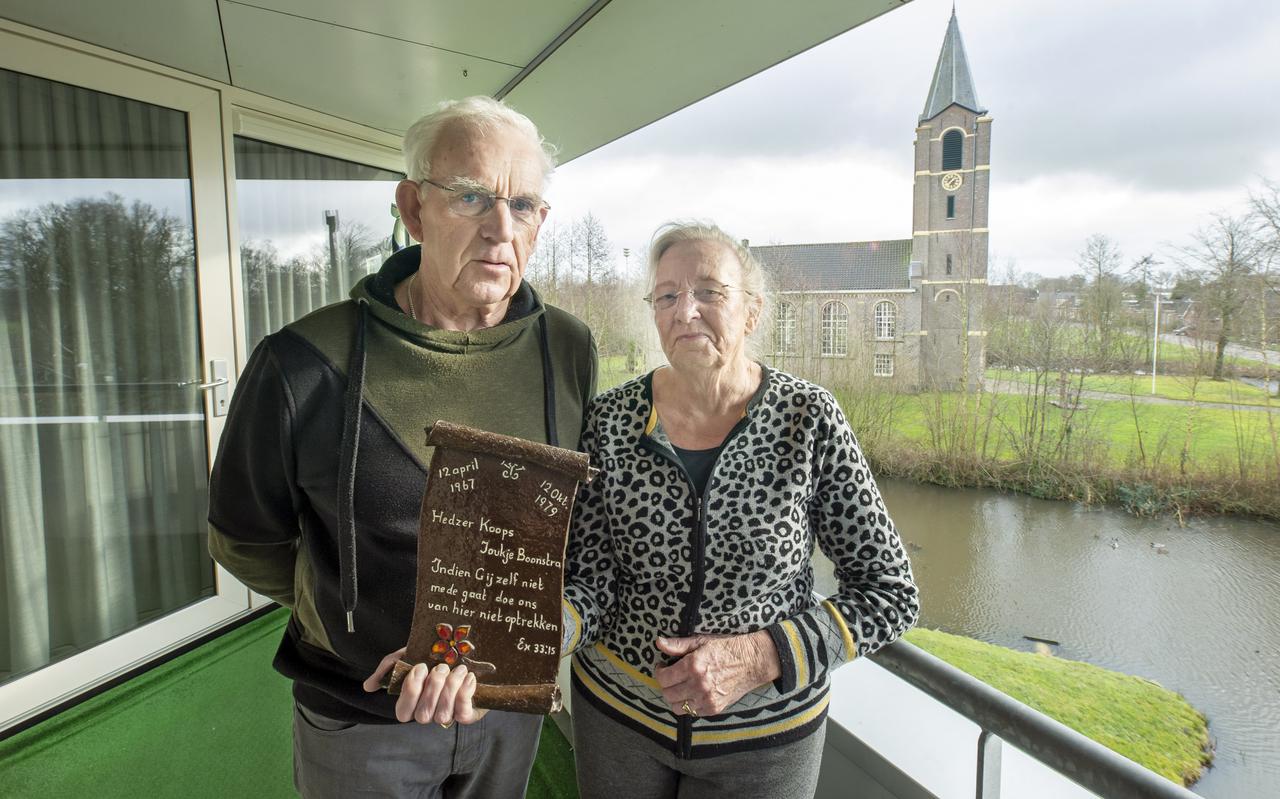 Hedzer en Joukje Koops met het wandbord met hun trouwtekst. Vanaf hun balkon zien ze uit op hun kerk, de Benedictuskerk. 