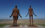 De twee beelden van het kunstwerk 'Wachten op hoog water' kijken vanaf de Waddendijk bij Holwert uit over het kwelderlandschap. 