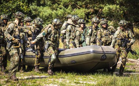 Militairen van de pantserinfanterie van de Koninklijke Landmacht dragen een rubberboot.