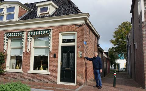 Piet de Haan op het midden van baan bij een hoekhuis op De Markt in Dokkum. 