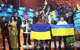 Leden van de Oekraïense band Kalush Orchestra vieren hun overwinning op het Eurovisie Songfestival 2022 in Turijn. Links staan de drie presentatoren.
