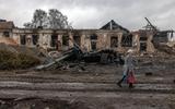 Een inwoner loopt langs een vernietigde Russische tank en stukgeschoten gebouwen in het centrum van Trostianets. 
