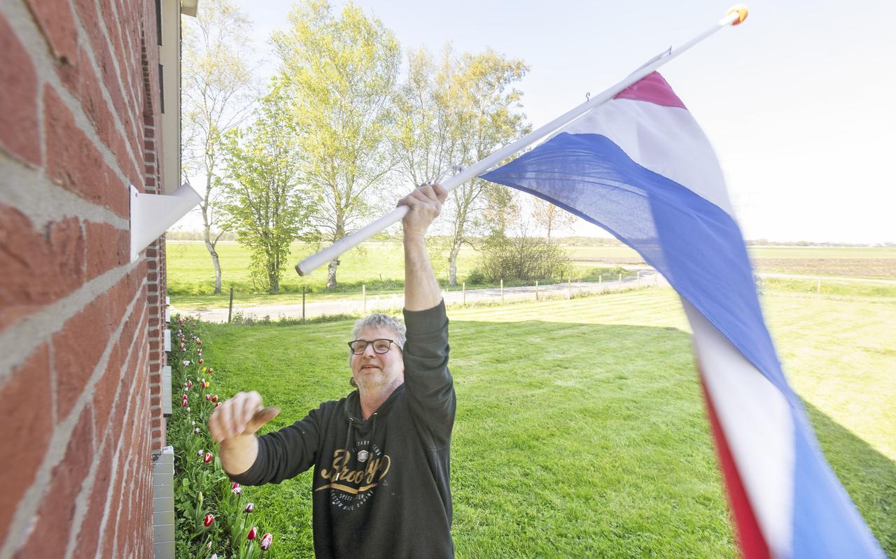 Frans Algra uit Tytsjerk hangt de vlag uit met de rode baan boven. Frans Algra uit Tytsjerk hangt de vlag uit met de rode baan boven.