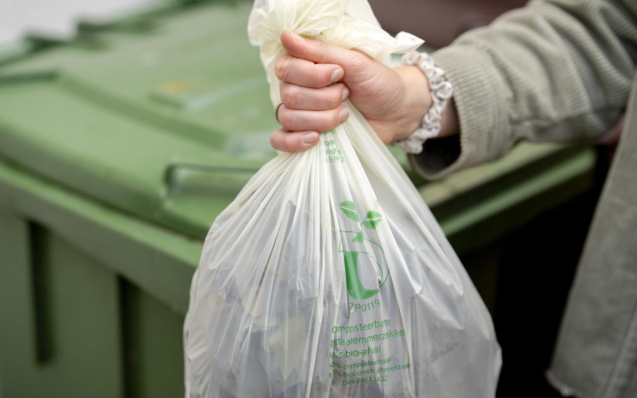 Een vrouw gooit gft-afval weg in de groene klikobak.