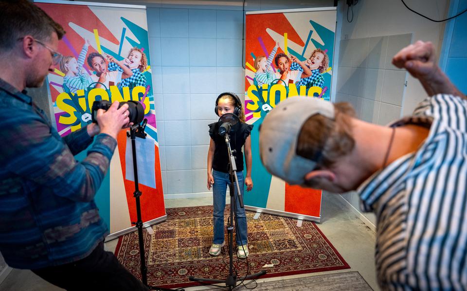 Raynaud Ritsma (rechts) moedigt Elisa Hoog aan terwijl ze het lied 'De Takomst' inzingt in de SjONG-studio. Links maakt Murk-Jaep van der Schaaf een opname voor sociale media. 