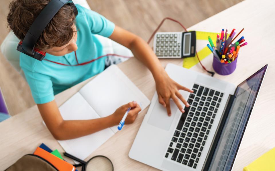 Een kind maakt huiswerk met een laptop.