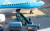 KLM-grondpersoneel laadt bagage in een vliegtuig.