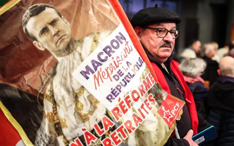 Een betoger in Toulouse met een protestbord waarop Macron staat afgebeeld als de machtige 'Zonnekoning' Lodewijk XIV. 