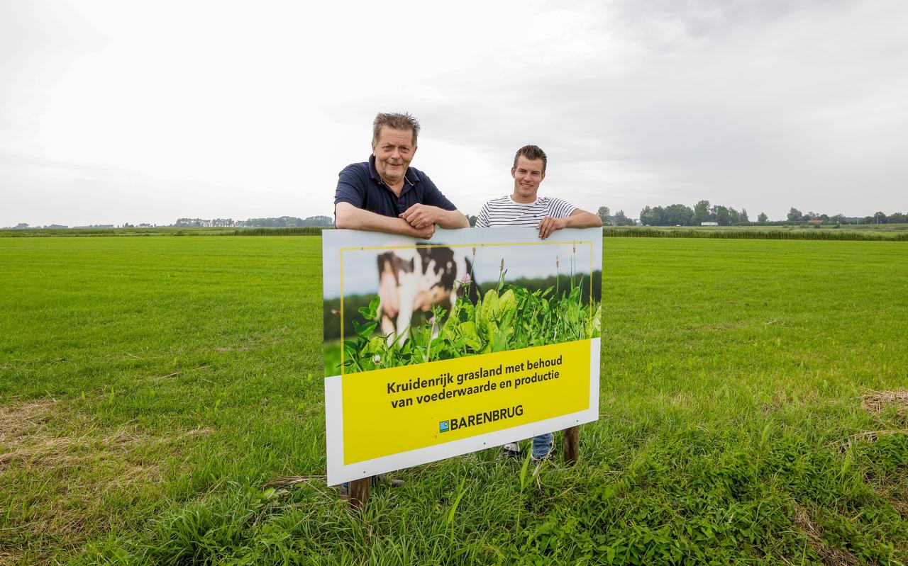 Jacob op de Hoek en zijn zoon Jouke poseren bij het bord Kruidenrijk Grasproject Urgenda in Tjerkgaast. 
