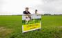 Jacob op de Hoek en zijn zoon Jouke poseren bij het bord Kruidenrijk Grasproject Urgenda in Tjerkgaast. 