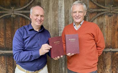 Kees Schafrat (links) en Herman Finkers met de eerste editie van de Bijbel in het Twents. 