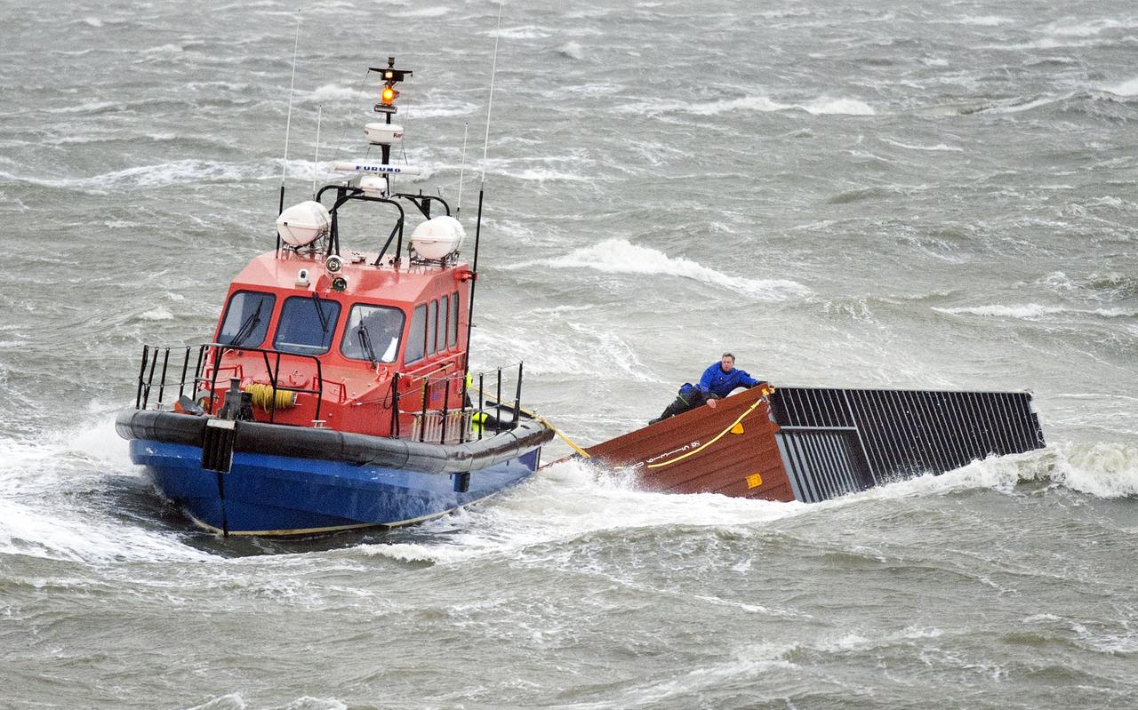 Een sleepboot sleept bij Lauwersoog een zeecontainer van de MSC Zoe naar de kust. 