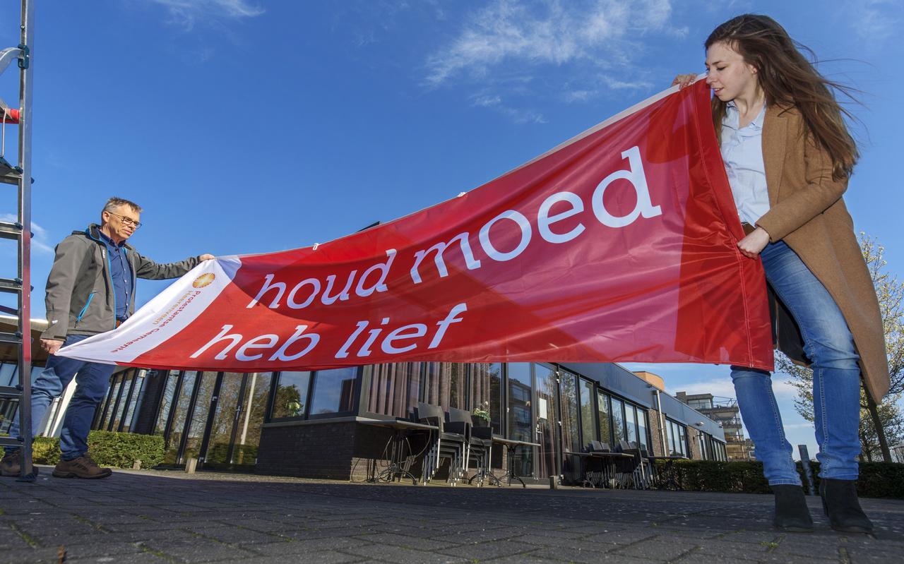 Maart 2020 :vlaggen met de tekst 'Houd moed, heb lief'. in Heerenveen. Links: beheerder Tonny van Balen, rechts ds. Anne-Meta Kobes, die actie mede bedacht. Maart 2020 :vlaggen met de tekst 'Houd moed, heb lief'. in Heerenveen. Links: beheerder Tonny van Balen, rechts ds. Anne-Meta Kobes, die actie mede bedacht.