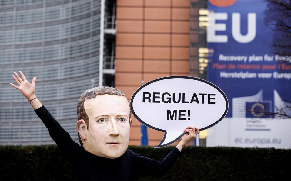 Een demonstrant met een masker op van Facebook-baas Mark Zuckerberg pleit voor het Berlaymont-gebouw van de Europese Commissie voor regulering van Big Tech, december 2020. 