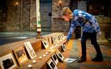 Stille Zaterdagviering in de Bonifatiuskerk in Oldeberkoop. Bauke de Vries steekt een kaarsje aan bij foto's van slachtoffers van de oorlog in Oekraïne. 
