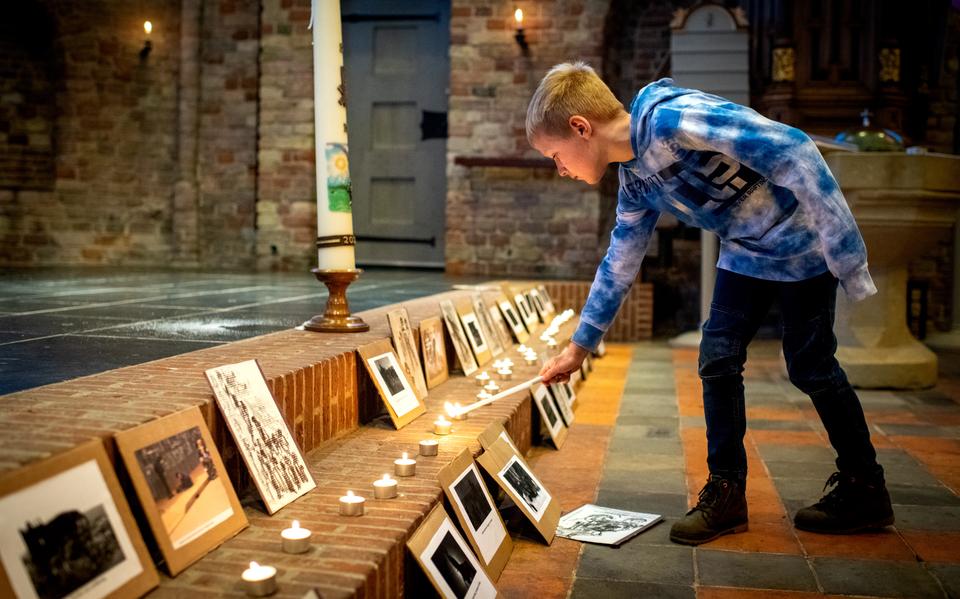 Stille Zaterdagviering in de Bonifatiuskerk in Oldeberkoop. Bauke de Vries steekt een kaarsje aan bij foto's van slachtoffers van de oorlog in Oekraïne. 