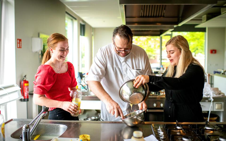 Daniëlle van der Veen (links) en Silke Vrieswijk krijgen instructies van chefkok Leendert Klaassens bij het maken van mayonaise.
