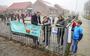 Roel de Jong, wethouder van de gemeente De Fryske Marren hangt samen met leerlingen van De Trieme een banner aan het hek van de school.