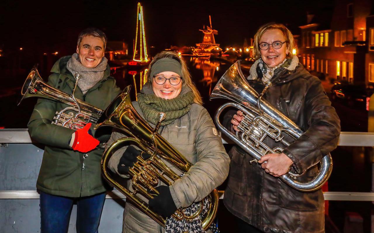 Annewiep Bloem (links), Aletta Miedema (midden) en Anneke Yntema op de brug over de Ie in Woudsend. Zij zullen de dorpsgenoten zaterdagmorgen verrassen met kerstmuziek op hun baritons.