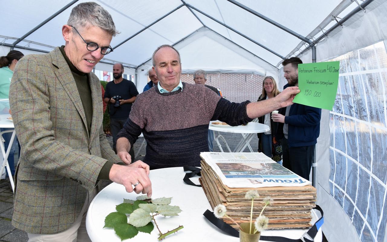 Burgemeester André van de Nadort pakt de 50.000e plant van Herbarium Frisicum in onder het toeziend oog van Karst Meijer. 