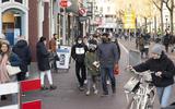 Winkelend publiek met de fiets aan de hand op de Wirdumerdijk in Leeuwarden. Afbeelding ter illustratie.