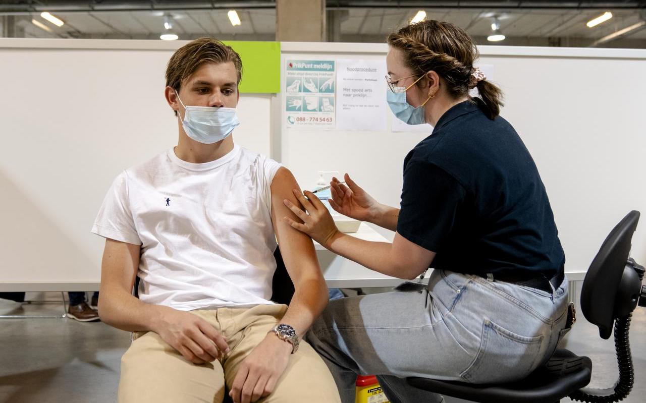 Een GGD-medewerker dient een coronavaccin toe aan een jongere. Een GGD-medewerker dient een coronavaccin toe aan een jongere.