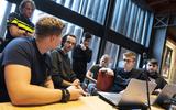 Een groep studenten buigt zich in de raadzaal van Leeuwarden over de aanpak van handelsfraude. Links politieagent Barend Frans.