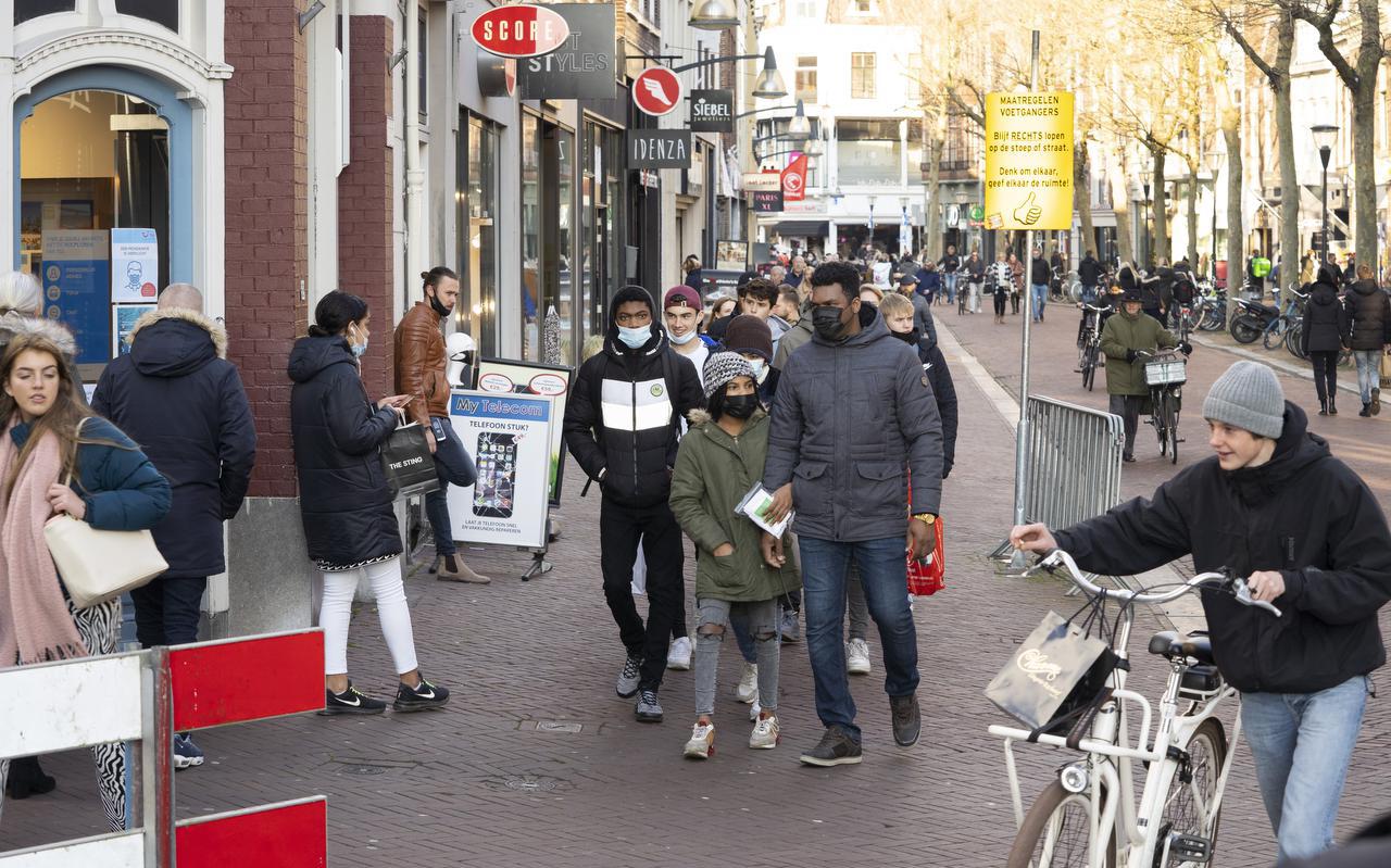 Winkelend publiek met de fiets aan de hand op de Wirdumerdijk in Leeuwarden. 