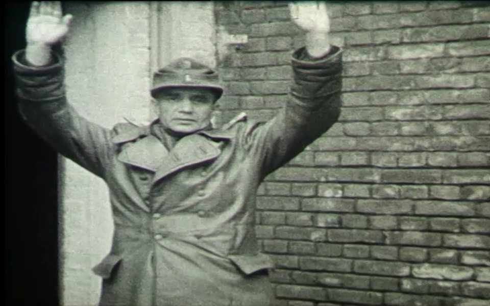 Een Duitse gevangene steekt zijn handen omhoog.